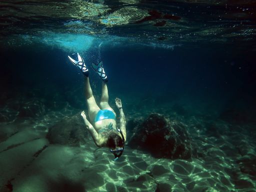 A female diver diving in the sea wearing snorkel goggles and fins