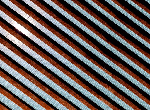 An aerial shot of solar panels in a field under the sunlight - environmental concept