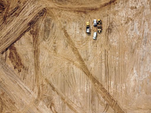 An aerial shot of road construction equipment on an open field