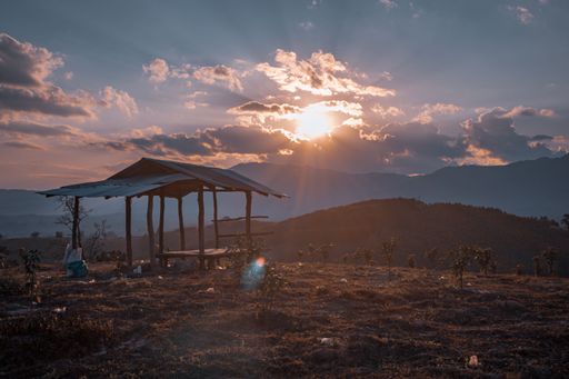 A beautiful sunset view of a garden umbrella in the middle of the field