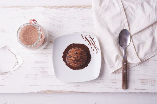A top view of chocolate ice cream scoop with chocolate topping and a cup of coffee