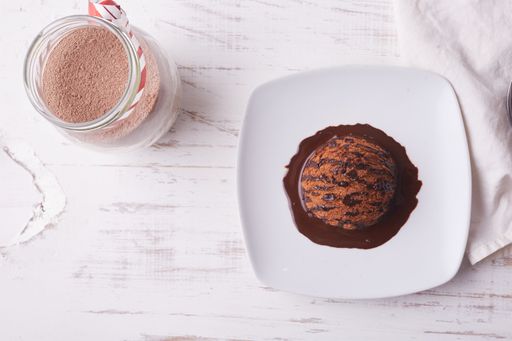 A top view of chocolate ice cream scoop with chocolate topping and a cup of coffee