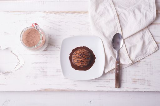 A top view of chocolate ice cream scoop with chocolate topping and a cup of coffee
