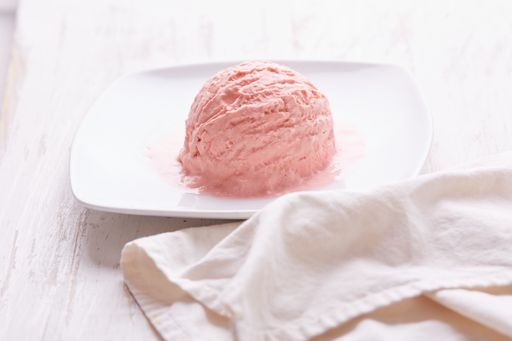 A top view of pink ice cream scoop on white plate