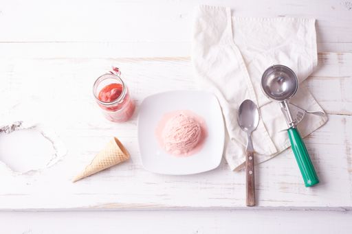 A top view of pink ice cream scoop on white plate