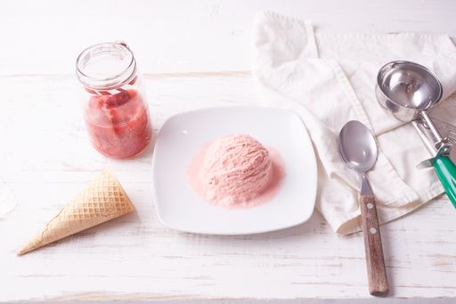 A top view of pink ice cream scoop on white plate