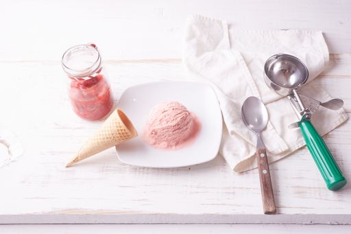 A top view of pink ice cream scoop on white plate