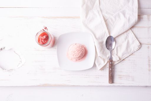 A top view of pink ice cream scoop on white plate