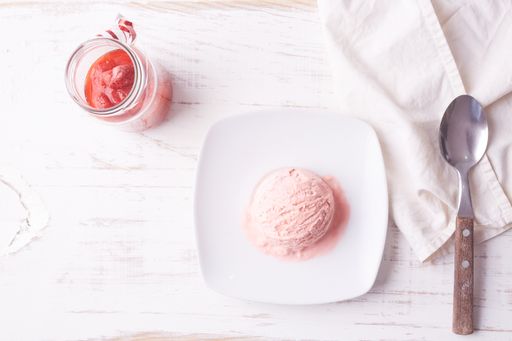 A top view of pink ice cream scoop on white plate