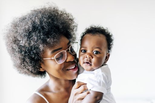 An African-American mother taking care and loving her baby against a white background