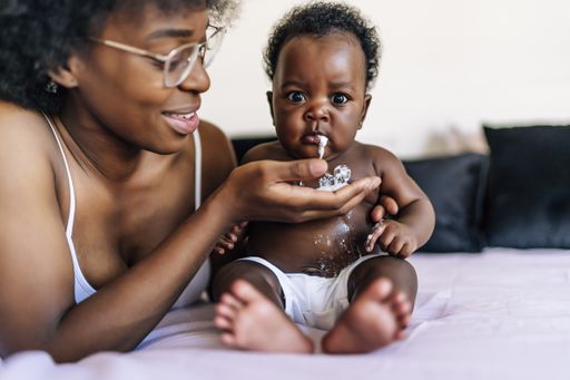 An adorable African-American baby vomiting milk in her mother's hand
