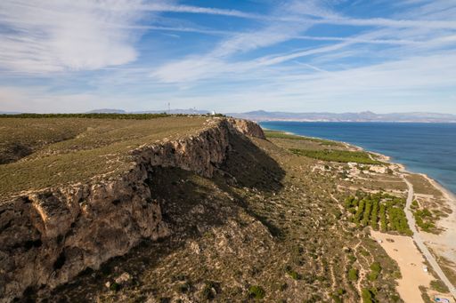 A beautiful drone view of the Calas del Aljub beach with the turquoise sea surrounded by hills in Santa Pola, Alicante, Spain