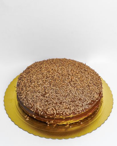 A vertical shot of a delicious cake covered in ganache and decorated with chocolate shavings