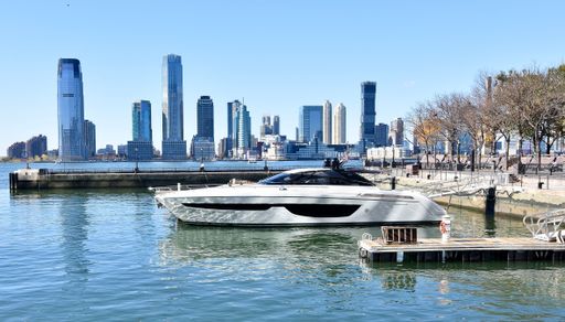 A white yacht moored in the Hudson River with high skyscrapers in Manhattan on a sunny day