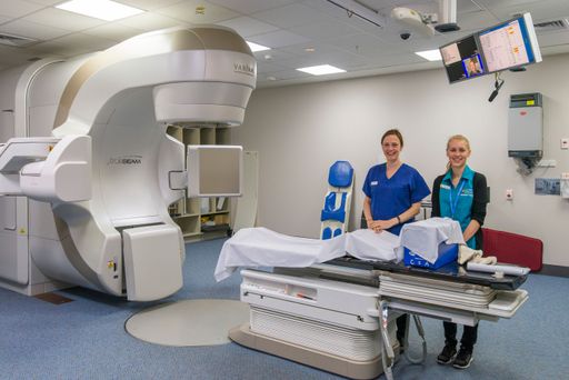 Two nurses beside a  radiation therapy "Varian True Beam" CT scanner
