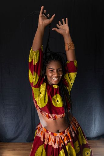 Young woman wearing colorful long clothes over black background. Natural expression.