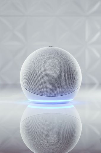 A vertical shot of Amazon Echo 4 with neon blue led light on the bottom part on the white table in background of shiny white textured walls
