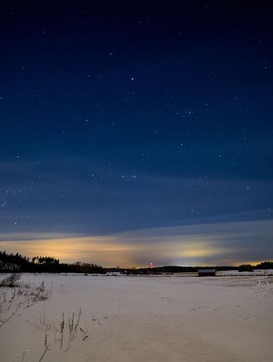 A vertical shot of beautiful a starry night with Northern lights (aurora borealis) in winter