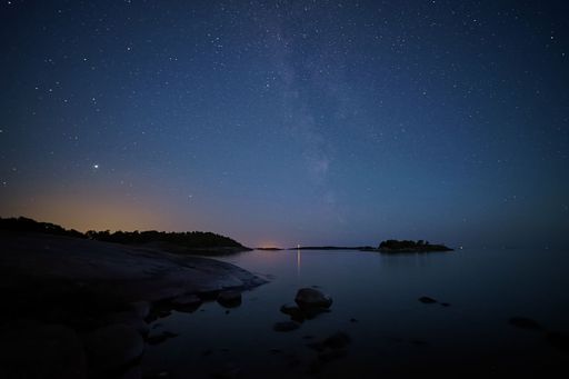 A lake reflecting the starry sky with trees and a night sky in the background, perfect for wallpapers