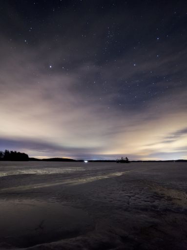 A vertical shot of a frozen lake with a starry night sky in the background, perfect for wallpapers