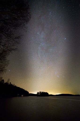 A vertical shot of a frozen lake with a starry night sky in the background, perfect for wallpapers