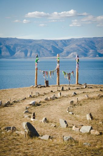 A vertical shot of wooden shaman totems with rock-lined pathways going up to them near Lake Baikal