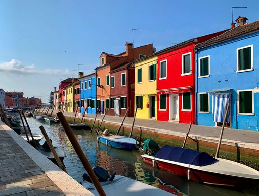 A beautiful shot of colorful houses and stores on the shore of the canal in Burano, Italy