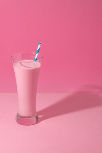 A glass of strawberry smoothie isolated on pink background