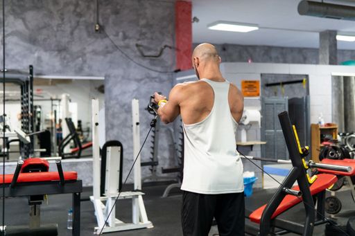 Back view of a caucasian young man doing biceps exercices in the gym, workout concept, copy space
