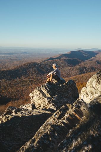 A young guy standing on a rock in the Blue Ridge Mountains on a sunny day, Virginia, United States