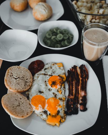 A traditional breakfast at the restaurant with bacon, fried eggs, buns and cup of coffee