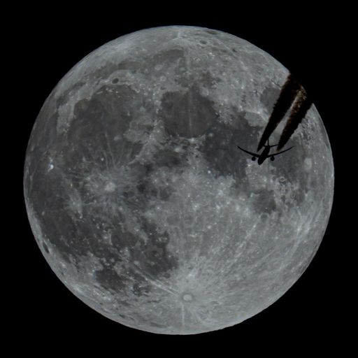 An airplane flying in the sky at night with the Moon in the background