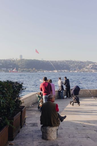 A man sitting near the sea with people in the background in Istanbul in Turkey