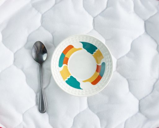 An overhead shot of a plate and a spoon on a white fabric