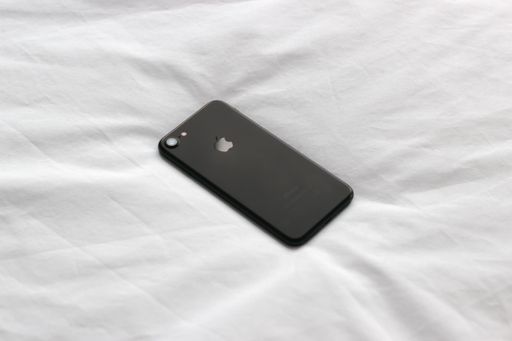 A high angle shot of an iPhone in a black case on a white blanket