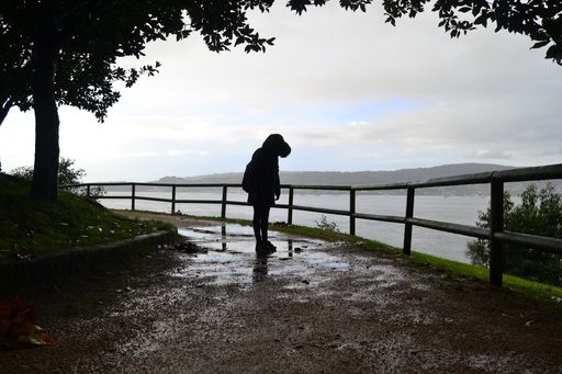 A person in a hooded jacket standing near a lak