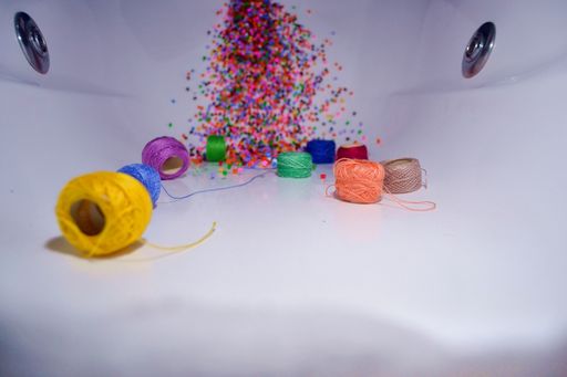 A closeup shot of colorful thread rolls and beads on a white surface