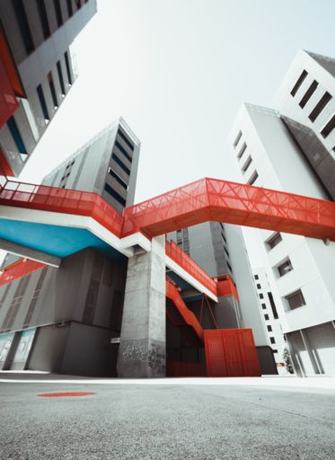 A vertical shot of a modern building with a red staircase and bridge