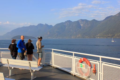 The passengers on the deck of the BC Ferry near Vancouver with mountains and the ocean in the background
