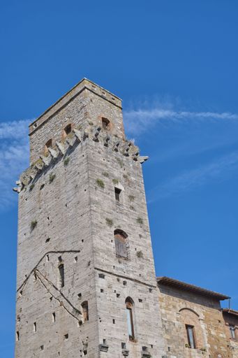 A low angle of the Cistern Square tower against the bright sky in San Gimignano, Tuscany, Italy