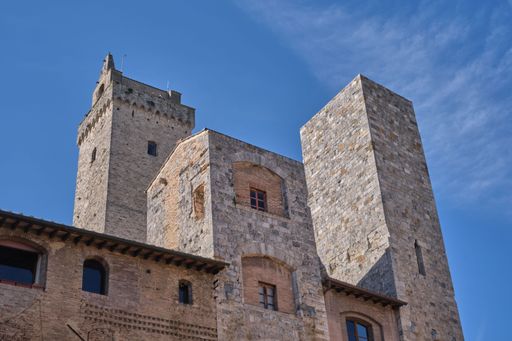 A low angle of the Ardinghelli Towers against the bright sky in San Gimignano, Tuscany, Italy