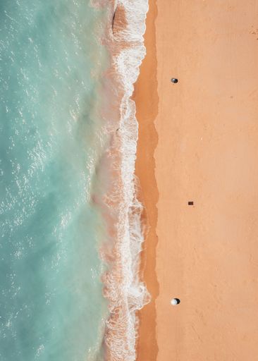 A top view of the Skopa beach waves washing on the sandy shore with umbrellas in Greece