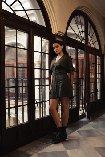 A vertical closeup of an attractive female posing next to an old glass door