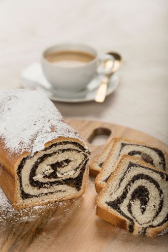 The vertical high-angle view of a sliced Swiss roll and a cup of cappuccino