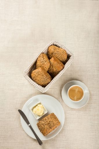 The vertical top view of a simple breakfast with butter, bread, and a cup of coffee