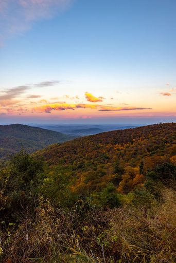 A vertical shot of the Shenandoah National Park with forests and hills under a sunset sky