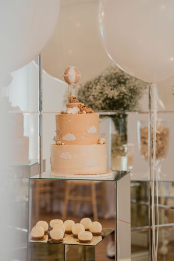 A vertical shot of a two-tier child birthday cake decorated with clouds, bears, and stars