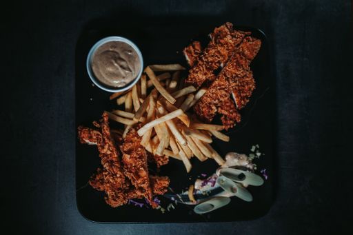 A top view  of the delicious roasted chicken with fried potatoes and sauce on the plate