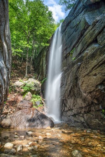 A vertical long exposure shot of a small waterfall in a park