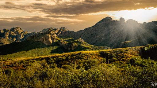A majestic sunset in front of a meadow and mountains with a beautiful cloudy sky in the background